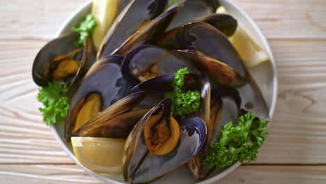 fresh mussels with herbs in a bowl with lemon