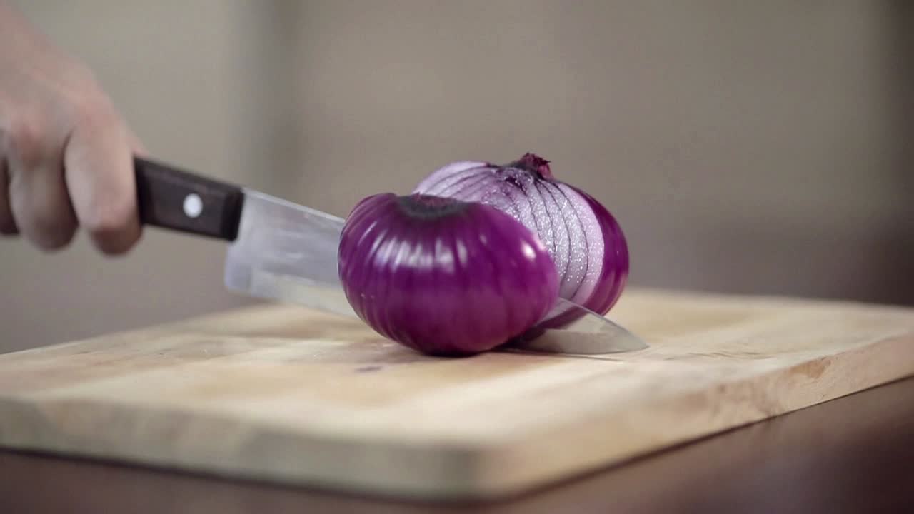 Cipolla rossa tagliata a metà su un tagliere di legno