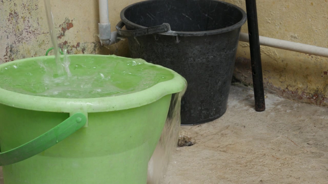 Overflowing Plastic Bucket with Water Spilling Over the Rim Outdoors Close Up