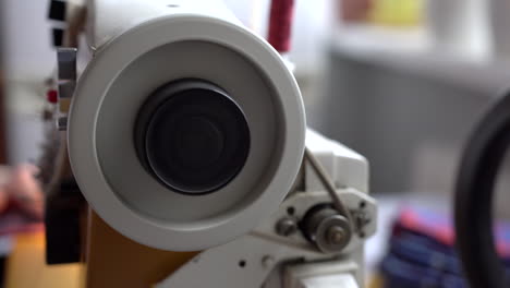 rueda giratoria en una máquina de coser blanca con un pequeño cinturón para transmitir la potencia