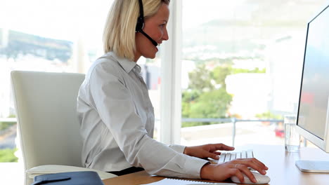 mujer de negocios hablando con auriculares y escribiendo