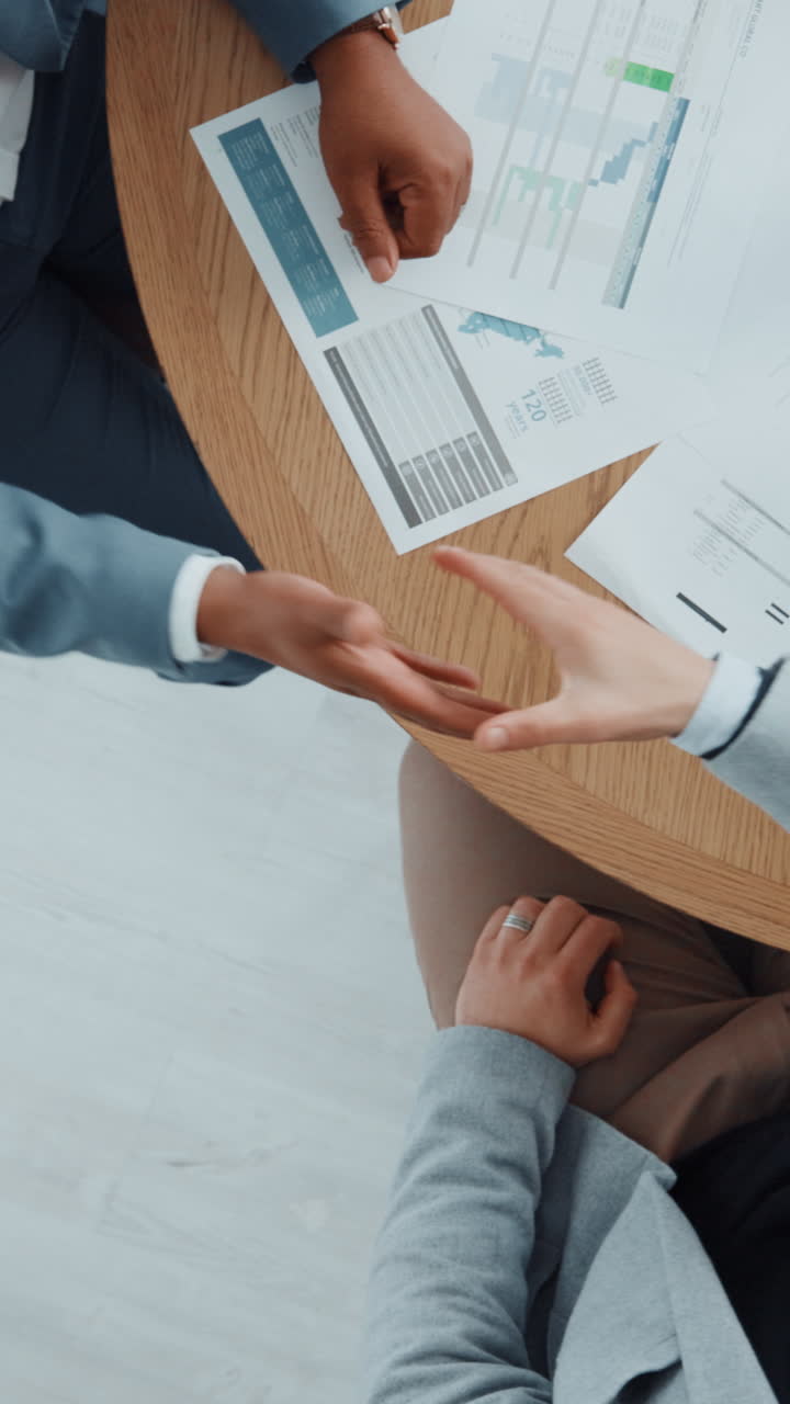 Persone d'affari che si stringono la mano sopra dei documenti sul tavolo