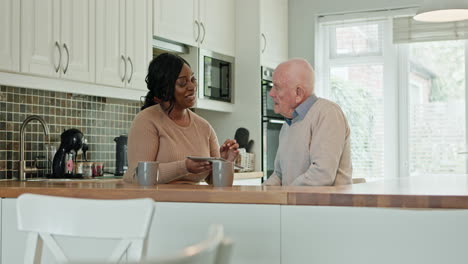 caregiver assisting senior man with tablet in kitchen