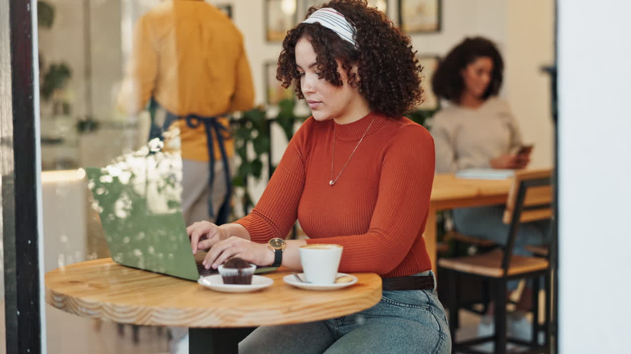 Woman working on laptop in cafe with coffee and cupcake