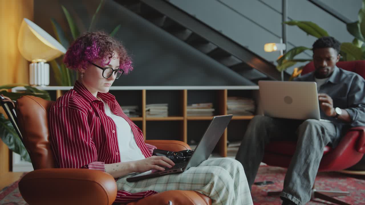 Woman with Prosthetic Arm Sitting Working on Laptop in Comfortable Office