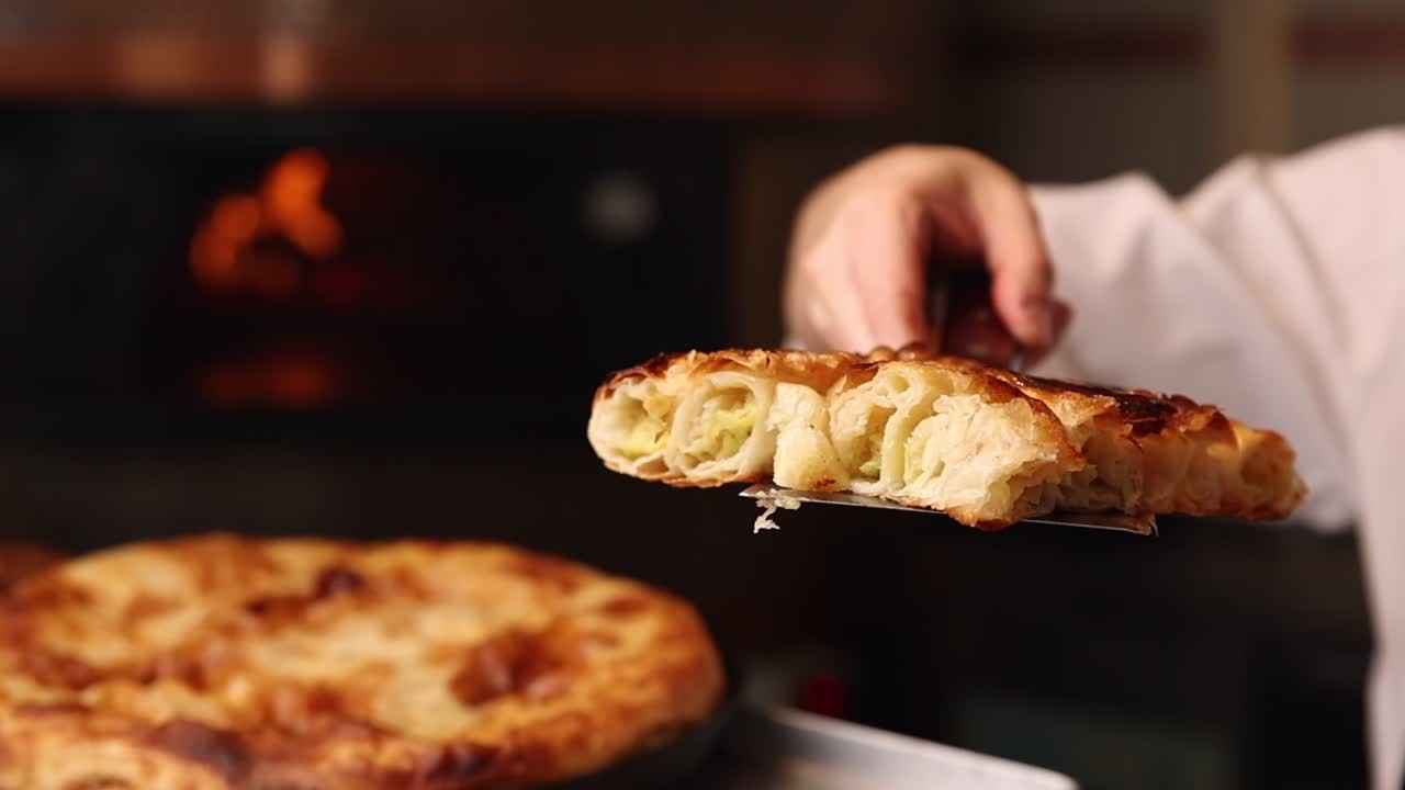 Chef che tiene una fetta di Burek appena sfornato