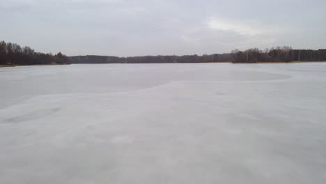 aerial: descending from height to the frozen lake surface on a cloudy day