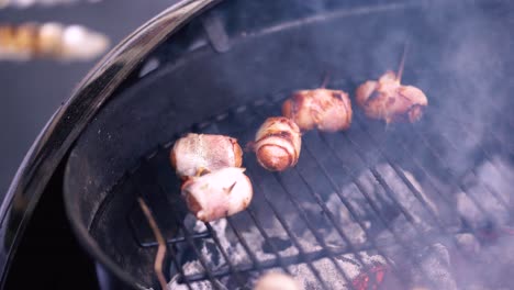 bacon-wrapped sausages on the grill