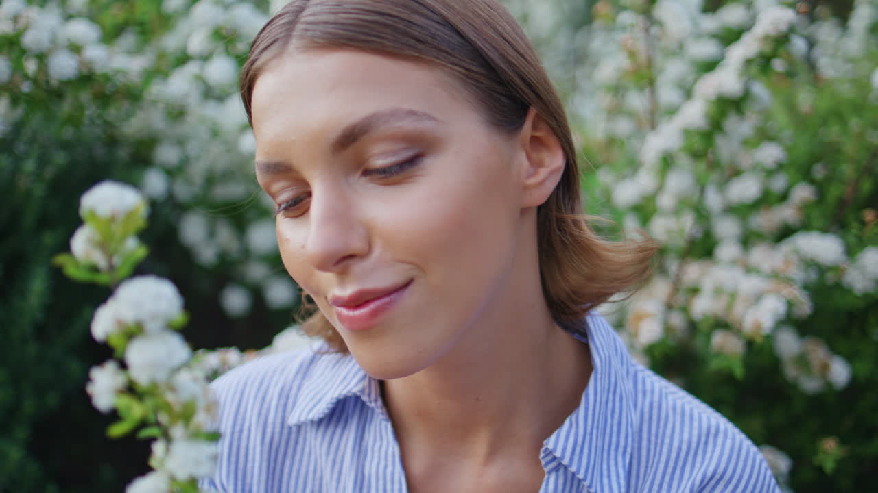 Lady enjoying flowers fragrance in garden closeup. Smiling happy woman