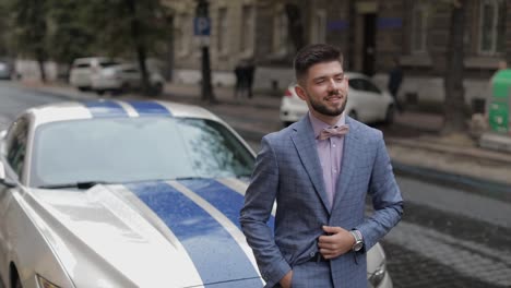 Groom-near-sport-car-on-street.-Pink-shirt,-bow-tie,-blue-jacket.-Businessman