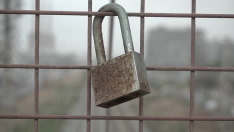 dolly in and out of an old rusty love lock hanging on the iron fence of a train bridge