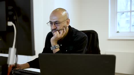 Focused employee concentrating on work, using a laptop while strategizing and analyzing solutions to complex problems in a corporate setting