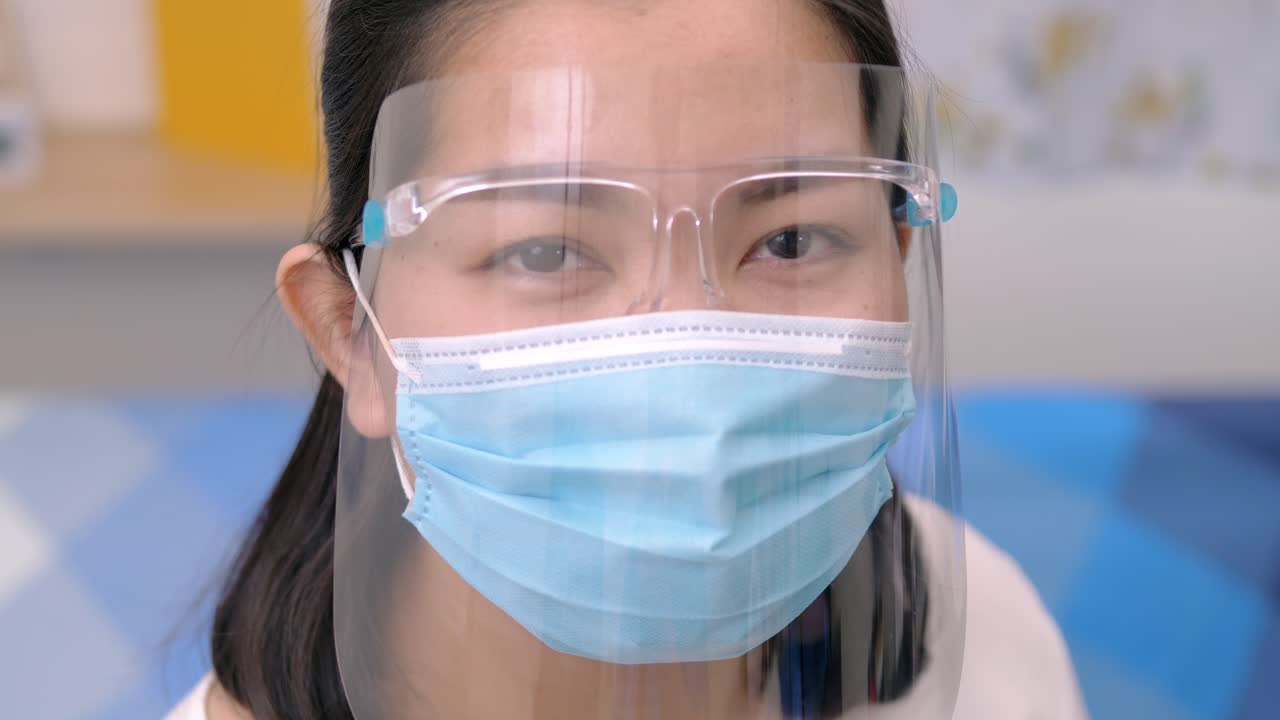 retrato de una joven asiática que lleva un protector facial con una máscara redondeada alrededor de la cara desde una perspectiva frontal para proteger sus gafas y ojos, escena de cámara lenta