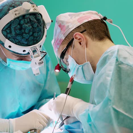 group of medical specialists during surgery. professional doctors in medical masks and caps work with surgical equipment. health care concept.