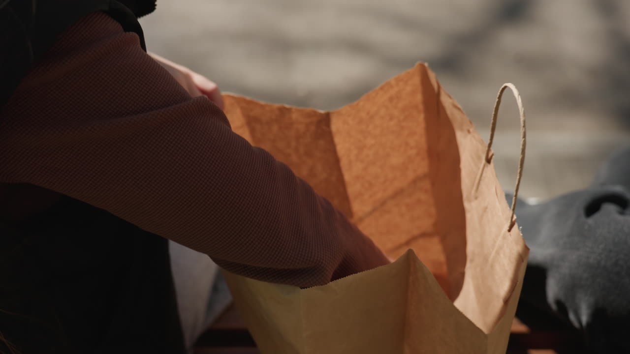 Unos amigos examinan artículos de artesanía al aire libre, dos amigos exploran pequeños objetos de arte en un parque, dos compañeros buscan materiales creativos en un banco durante una animada actividad en el parque
