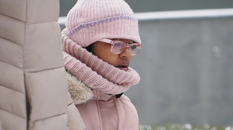 Young Girl in Pink Winter Clothes Looking Around and Putting on a Glove