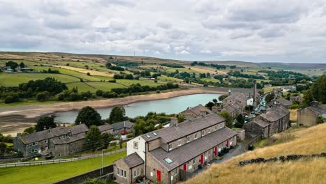 aerial footage of a rural industrial village with old mill and chimney stack