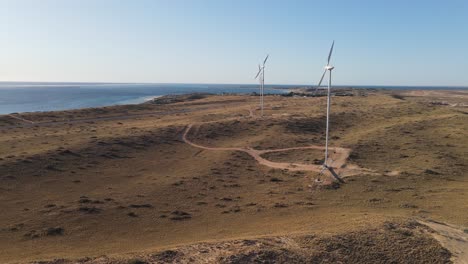 4K-Wind-turbines-front-to-sea-at-sunset-aerial-shot-renewable-energy-slow-motion