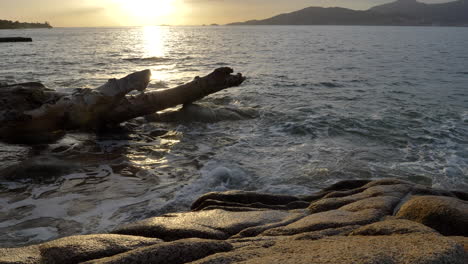 4k tranquil sunset ocean scene, waves over rocks and driftwood