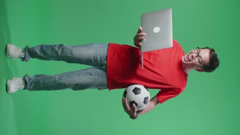 hombre celebrando la victoria del fútbol con una computadora portátil y una pelota de fútbol