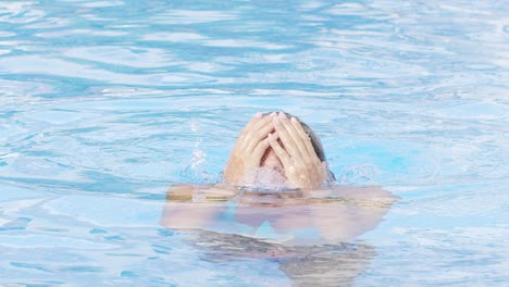 woman with blue bikini emerges from the pool