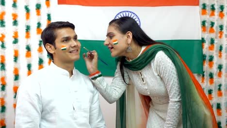 indian girl painting a flag on the face of the young boy - national flag. independence day concept