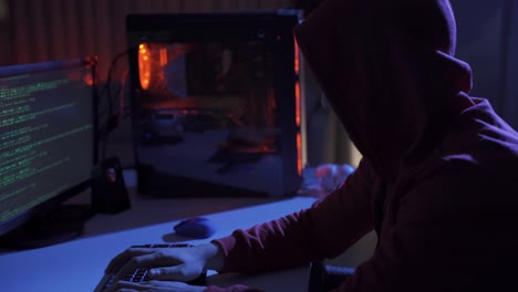 Side view of hacker sitting near computer monitors with green code screens.