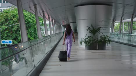 woman walking on a footbridge with suitcase