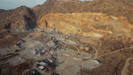 Stone-quarry-aerial-wide-shot-showing-winding-roads-and-heavy-machinery,-clear-sunny-day