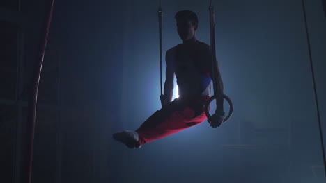 gymnast performing gymnastic cross exercise on gymnastic rings. shot in slow motion.