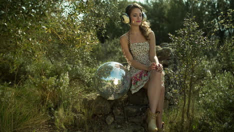 hermosa mujer sentada en una pelota de discoteca en la naturaleza