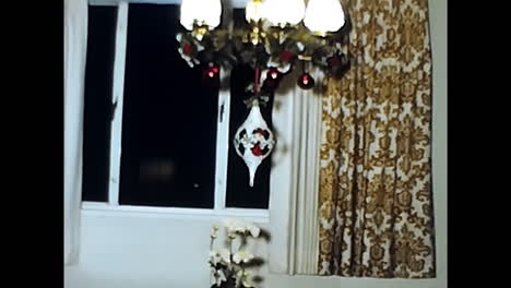 young boy decorates christmas tree. circa usa - 1970s: a young boy from a 1970s video archive in the usa decorates a christmas tree with ornaments and lights.