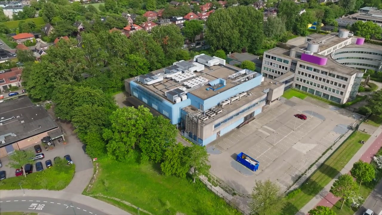 Aerial drone shot showing a modern datacenter and office park in a green Dutch suburban neighborhood