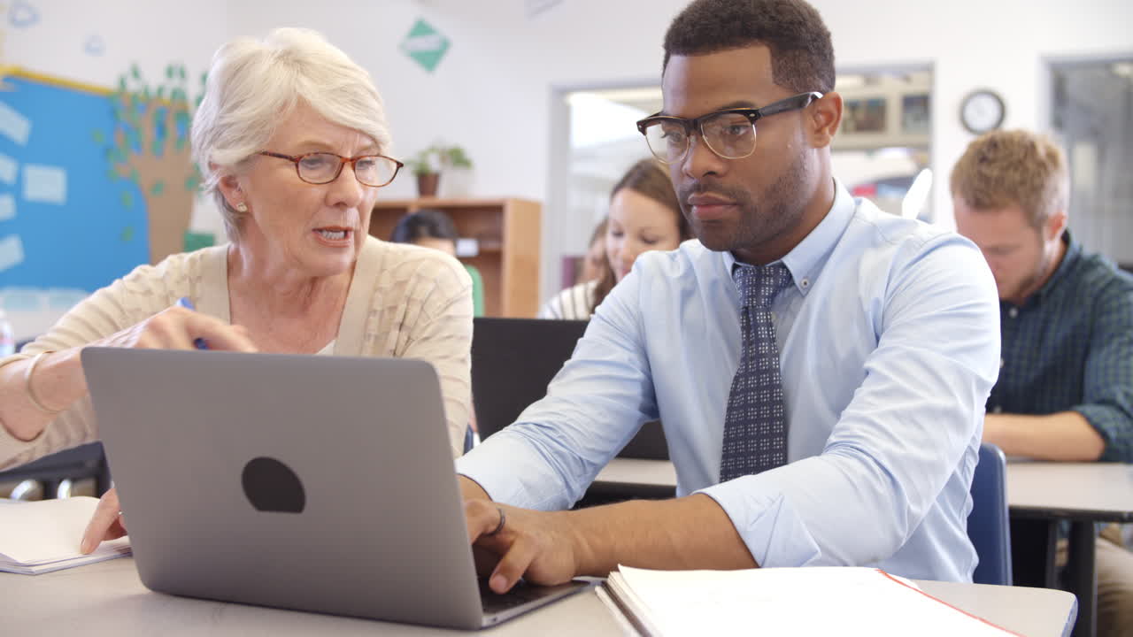 maestro y estudiante usando una computadora portátil en una clase de educación de adultos