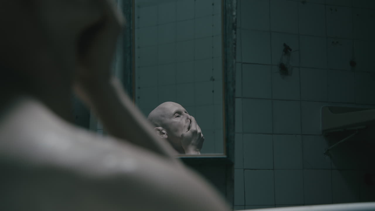 Pale bald skinny man takes a bath in the creepy old bathroom at night