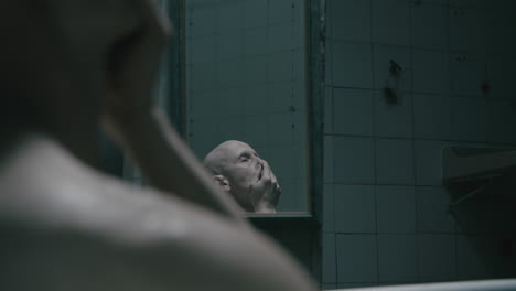pale bald skinny man takes a bath in the creepy old bathroom at night