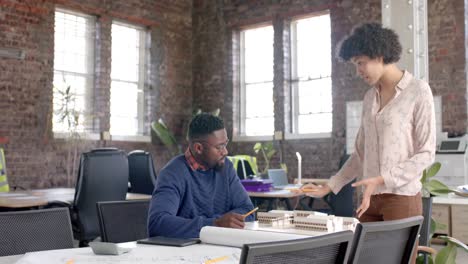 focused diverse architect colleagues discussing work with building model in office in slow motion