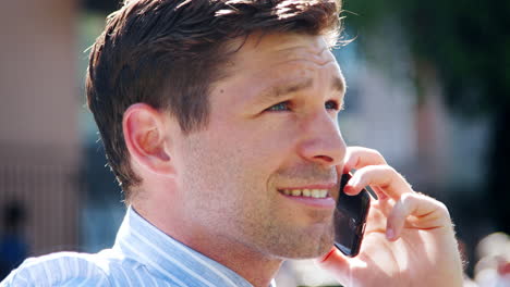 Businessman-Talking-On-Mobile-Phone-During-Lunch-Break-In-Park