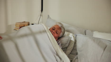 a nurse smiling at an elderly patient in a hospital bed