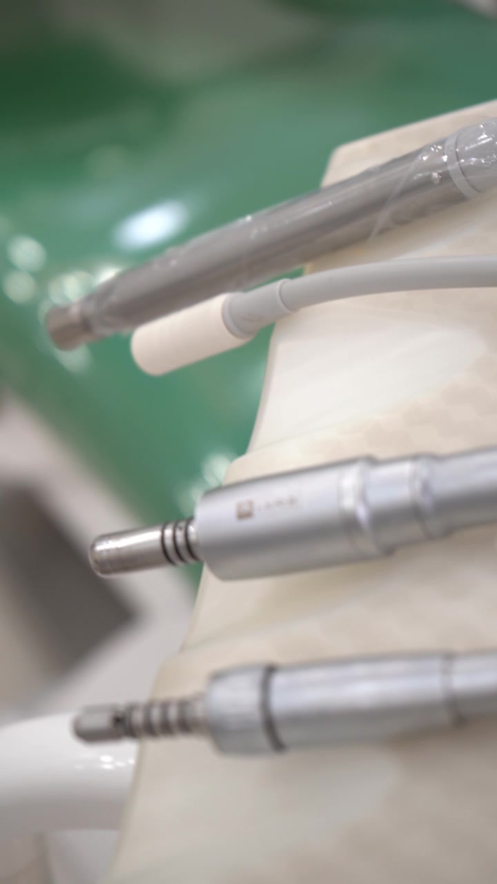 Macro shot of metallic dental drills and a suction tube on a delivery unit tray.