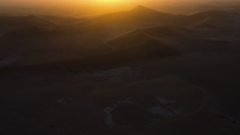 La-Inclinación-Aérea-Revela-Una-Puesta-De-Sol-Nebulosa-Sobre-Las-Dunas-De-Arena-Del-Desierto-En-África