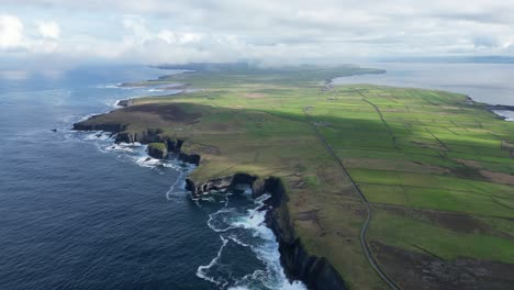 loophead peninsula with dramatic cliffs, lush green fields, and coastal roads under a cloudy sky, aerial view