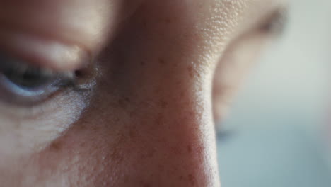 extreme close-up of a woman's face, focusing on the bridge of the nose and part of the eye