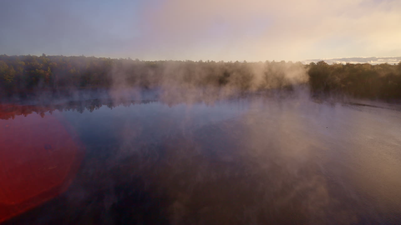 Aerial footage of mist rising from the water in soft dawn light