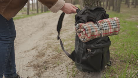 an unrecognizable adventurous female grabs her backpack and starts walking through the forest