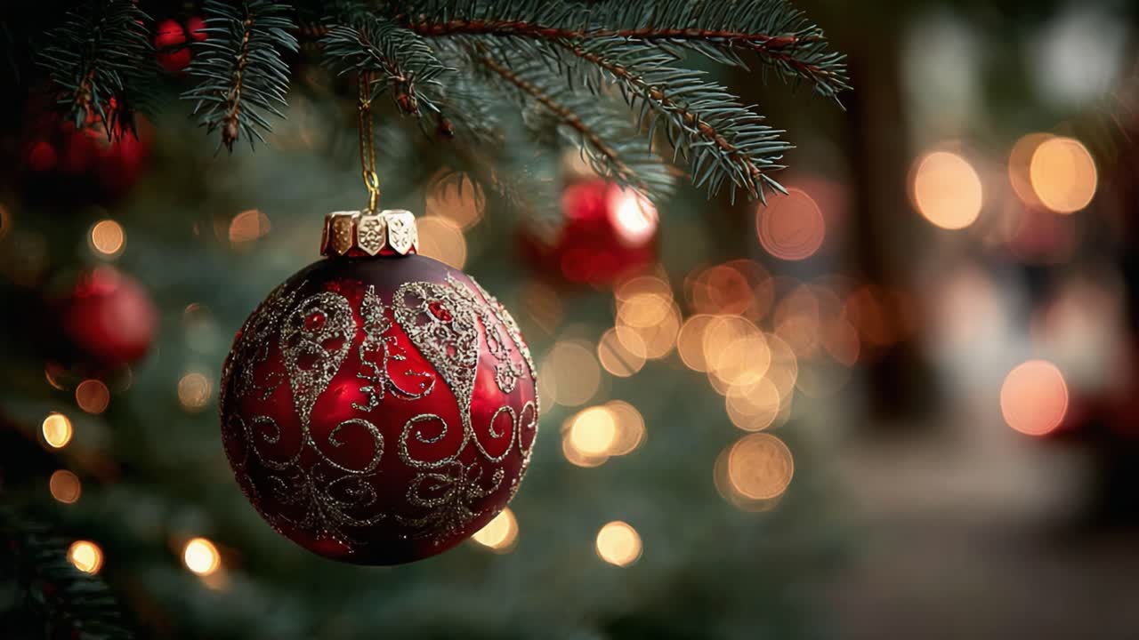 Un bellissimo ornamento natalizio rosso che brilla tra festosi rami di pino verdi, catturando il bagliore caldo delle luci natalizie sullo sfondo