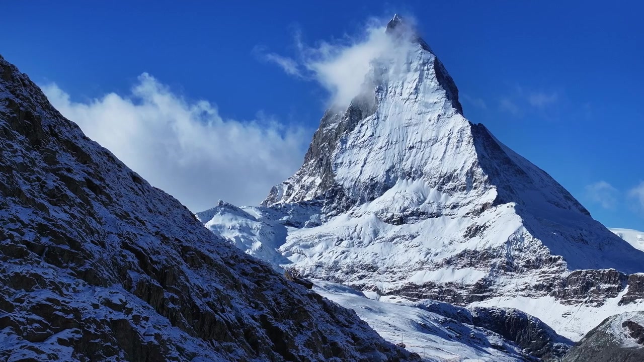 スイスアルプス、ツェルマット。リッフェルゼー湖に映るマッターホルンの有名な山頂、崖。風と霧、初冠雪、秋から冬の青空の朝、ゴルナーグラート鉄道が織りなすスイスの絶景をドローンが捉える。
