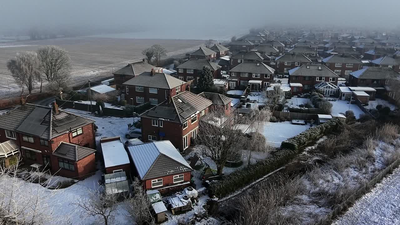 Chilly morning mist aerial view covering British small town neighbourhood houses and meadow