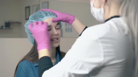 el maestro limpia las cejas de la mujer con un algodón en el salón