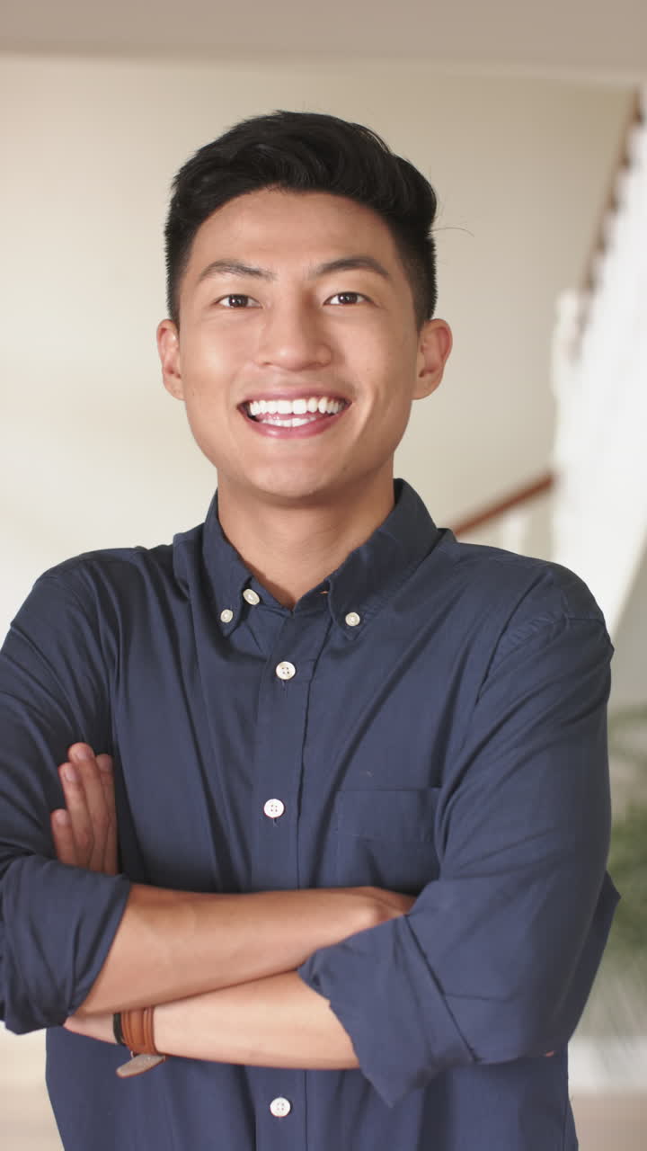 Vertical video of portrait of happy asian man at home, slow motion